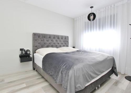 a bed in a white bedroom with a large window at Beautiful apartment in Akureyri in Akureyri