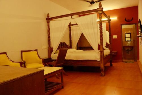 a bedroom with a canopy bed and two chairs at Vacation villa in Yercaud