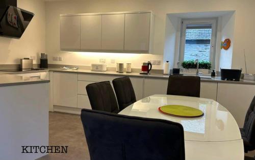 a kitchen with a white table and chairs and a counter at Annie’s Flat in Aberfeldy