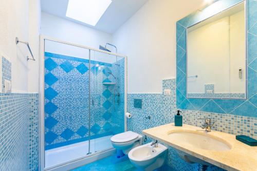 a blue bathroom with a toilet and a sink at Le Maschere B&B in Santa Teresa Gallura
