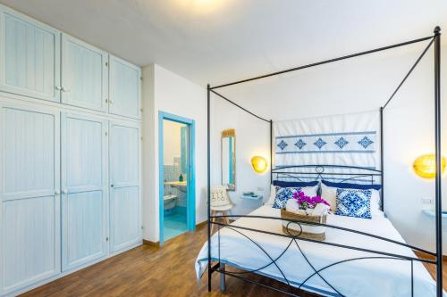 a bedroom with a canopy bed with blue accents at Le Maschere B&B in Santa Teresa Gallura
