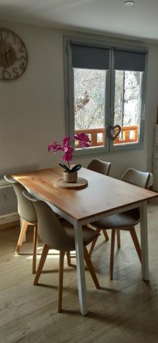 uma mesa de jantar com um vaso de flores em Appartement cosy au coeur du Mercantour em Valdeblore