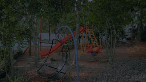 - une aire de jeux avec toboggan rouge dans les arbres dans l'établissement Mountain Vibes Resort Wayanad, à Wayanad