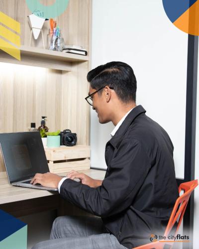 a man sitting at a desk using a laptop computer at The City Flats Amorsolo in Manila