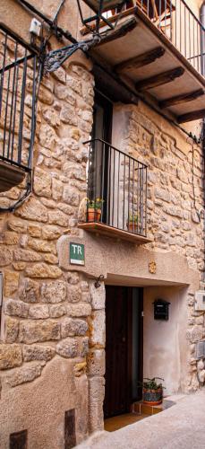 a stone building with a balcony and a door at La Casa del Castell - Encanto rural junto al Parque Natural de els Ports in Horta de San Joan