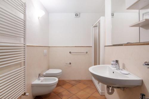 a white bathroom with a toilet and a sink at Residence Larice Bianco App n5 in Campodolcino