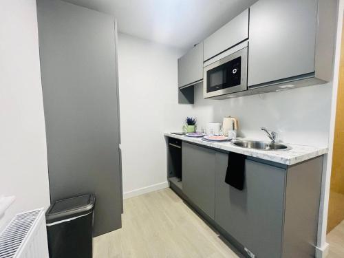 a small kitchen with a sink and a microwave at Contemporary Chic Studio in Stretford in Manchester