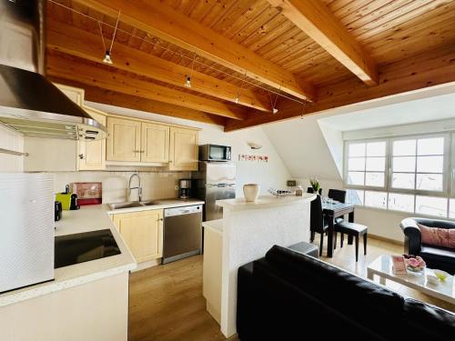 Il comprend une cuisine ouverte et un salon doté de plafonds en bois. dans l'établissement Appartement dans maison à colombages 6 personnes Les Sables, à Les Sables-dʼOlonne