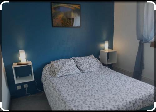 a blue bedroom with a bed and two lights on the wall at HOTEL LAC PAVIN in Besse-et-Saint-Anastaise