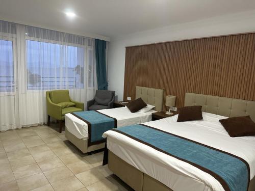 a hotel room with two beds and a chair at Dinc Pension in Bodrum City