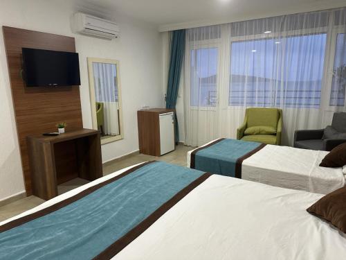 um quarto de hotel com duas camas e uma televisão de ecrã plano em Dinc Pension em Bodrum City