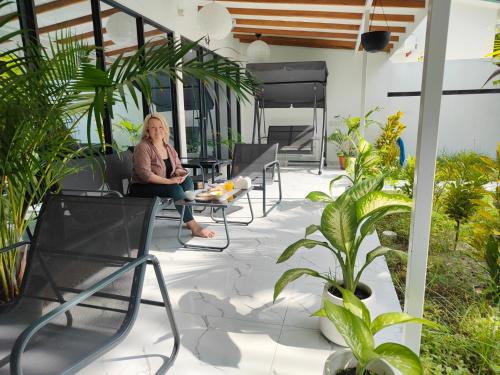 eine Frau auf einem Stuhl auf einer Terrasse mit Pflanzen in der Unterkunft Oceana Inn Maldives in Kudahuvadhoo