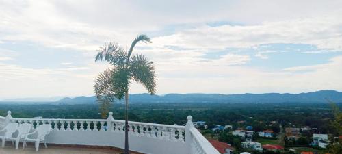 Elle comprend un balcon blanc avec des chaises et un palmier. dans l'établissement BELLA CRISTINA, à Ricaurte