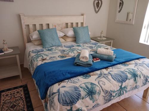 Una cama con sábanas azules y blancas y toallas. en Eagle's Rest, en Hartenbos