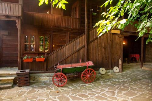 un edificio de madera con un vagón rojo delante de él en Guest Houses "Zlatna Oresha - Complex", en Zheravna