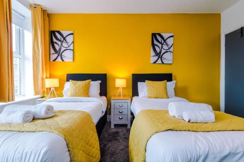 três camas num quarto com paredes amarelas em Barnes House - Sleeping 8 em Clayton le Moors