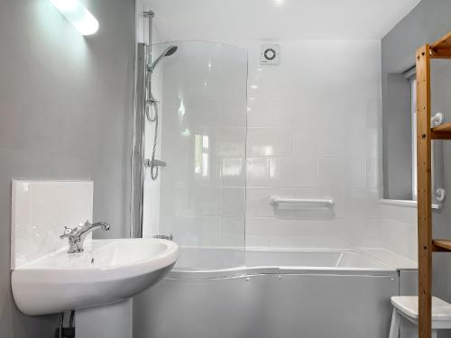 a white bathroom with a sink and a shower at Coldwell Street Cottage in Wirksworth