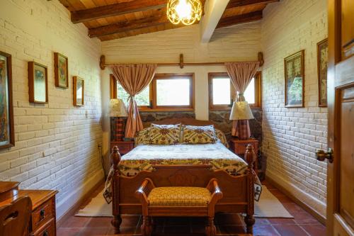 a bedroom with a bed and a chair and windows at Hotel Rancho San Cayetano in Zitácuaro