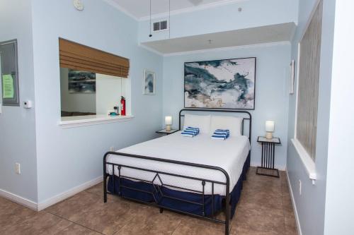 biała sypialnia z łóżkiem z niebieskimi poduszkami w obiekcie Villas at Destin West Gulfside V403 w mieście Fort Walton Beach