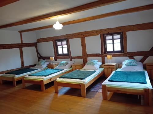 three beds in a room with wooden floors and windows at Rębiszów 50 in Rebiszów