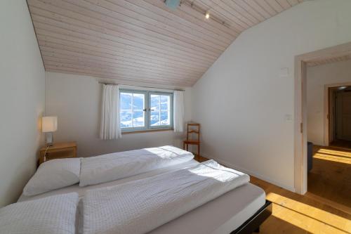 1 dormitorio con cama blanca y ventana en Undereggli, en Nesslau