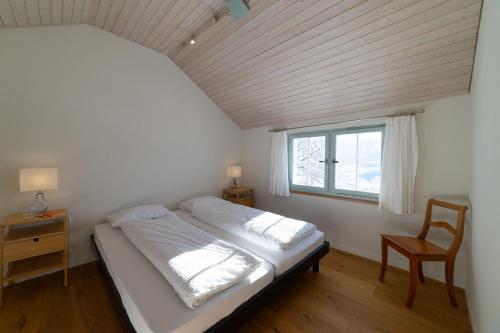 a bedroom with a bed and a chair and a window at Undereggli in Nesslau