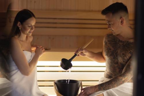 a man and a woman are cooking in a pot at Apartamenty Górskie Szlachtowa - jacuzzi i sauna w cenie - spokojna okolica in Szlachtowa