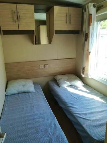 - 2 lits dans une petite pièce avec des armoires dans l'établissement Bungalow ensoleillé à Canet-en-Roussillon avec piscine partagéeA, à Canet
