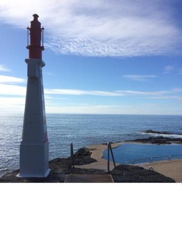 a lighthouse sitting on the edge of the ocean at Uma Casa na Caloura - Blue & Beach in Lagoa