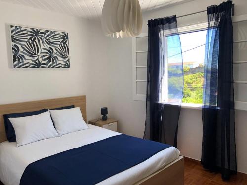 a bedroom with a bed and a window at Uma Casa na Caloura - Blue & Beach in Lagoa