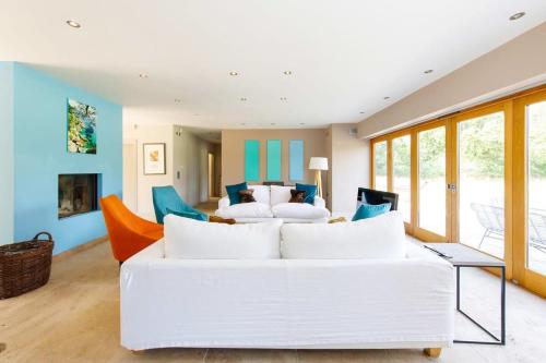 uma sala de estar com um sofá branco e cadeiras em Secluded barn style home with hot tub - sleeps 12 em Birdham