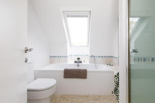 uma casa de banho com um WC, uma banheira e um lavatório. em Secluded barn style home with hot tub - sleeps 12 em Birdham
