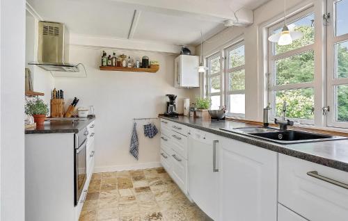 a kitchen with white cabinets and a sink and windows at Three-Bedroom Holiday Home In Stege in Stege