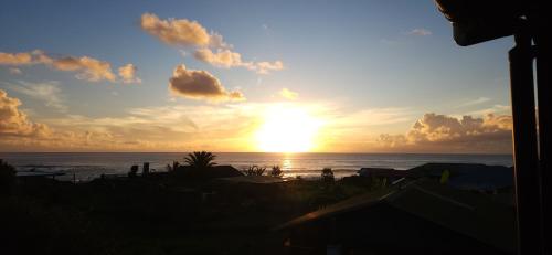una puesta de sol sobre el océano con el sol en el cielo en Cabañas Tupuna Lodge en Hanga Roa