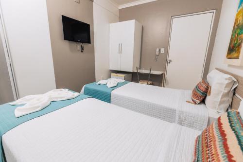 a hotel room with two beds and a tv at Pousada Capital das Águas in Maceió