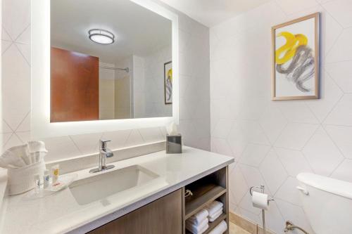 ein weißes Badezimmer mit einem Waschbecken und einem Spiegel in der Unterkunft Comfort Suites Whitsett in Whitsett