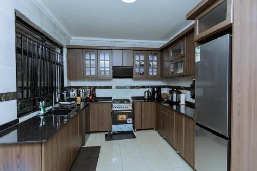 a large kitchen with wooden cabinets and a stainless steel refrigerator at Nice Homes Villa in Kigali