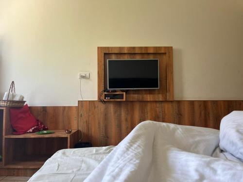 a bedroom with a bed and a tv on a wall at Hotel Obsidian Red in Gorakhpur