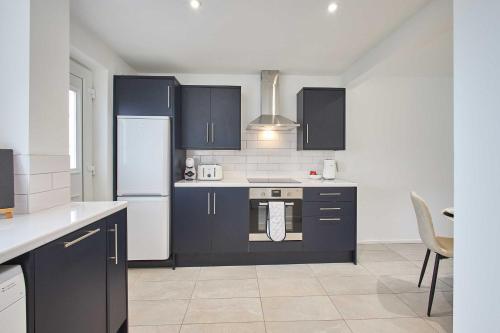 een keuken met blauwe kasten en een witte koelkast bij Host & Stay - Marsden Beach House in South Shields