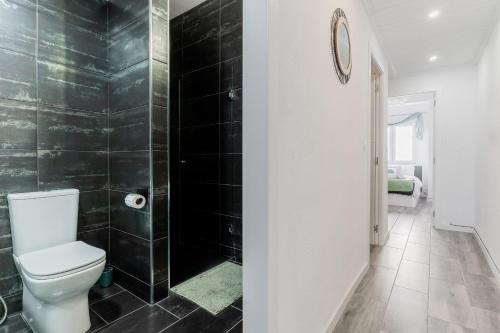 a bathroom with a toilet and black tiled walls at Enjoy Valencia: Deluxe Apartment with Terrace in Valencia