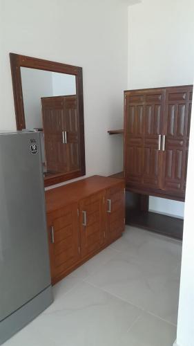 a kitchen with wooden cabinets and a mirror and a refrigerator at Oruwa Turtle Beach Villa in Kosgoda