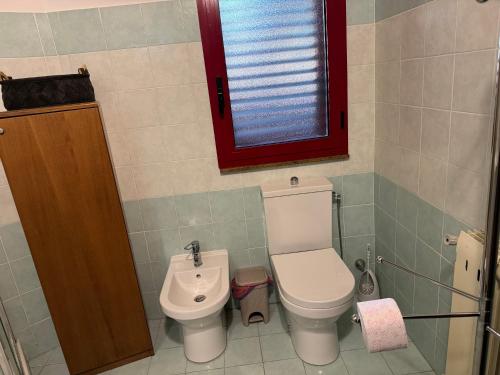 a small bathroom with a toilet and a window at Villa Rama in Aci Castello