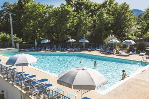 a swimming pool with umbrellas and chairs and people in it at Rez de Jardin Piscine et Plage in Poggio-Mezzana