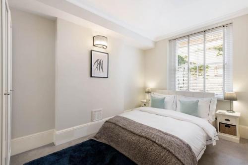 a white bedroom with a bed and a window at Beautiful Royal Borough Apartment in London