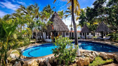 a swimming pool in front of a resort with palm trees at Hotel Margarita Village in Porlamar