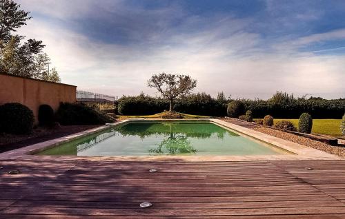 a pool of water in a yard with a wooden deck at Le Mas De La Vigne in Violès