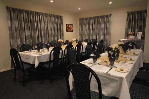 a dining room with long tables and chairs with flowers on them at Rocky Gardens Motor Inn Rockhampton in Rockhampton