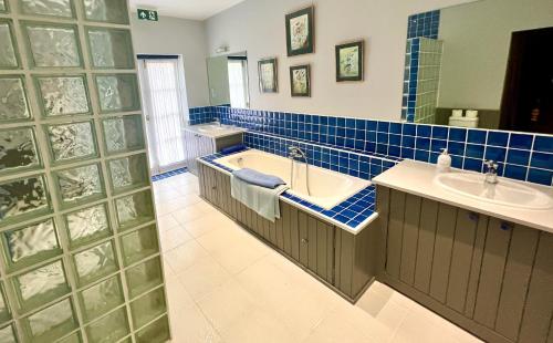 a blue tiled bathroom with a tub and a sink at The Mill House in Santon
