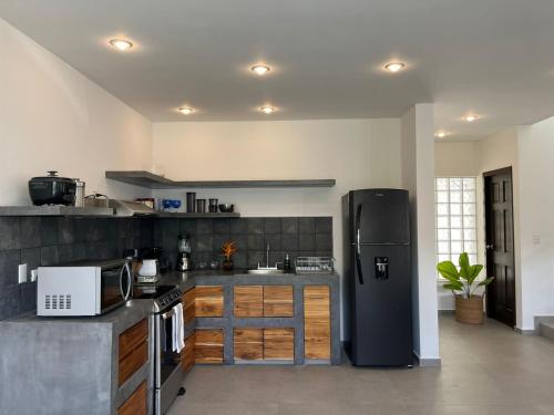 a kitchen with a black refrigerator in a room at Solemar 2bdrm House - Private Pool , King Bed and Balcony Sunset View in Mal País