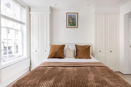 Historic Joseph Conrad House in Heart of London! في لندن: غرفة نوم مع سرير كبير مع وسائد بنية اللون